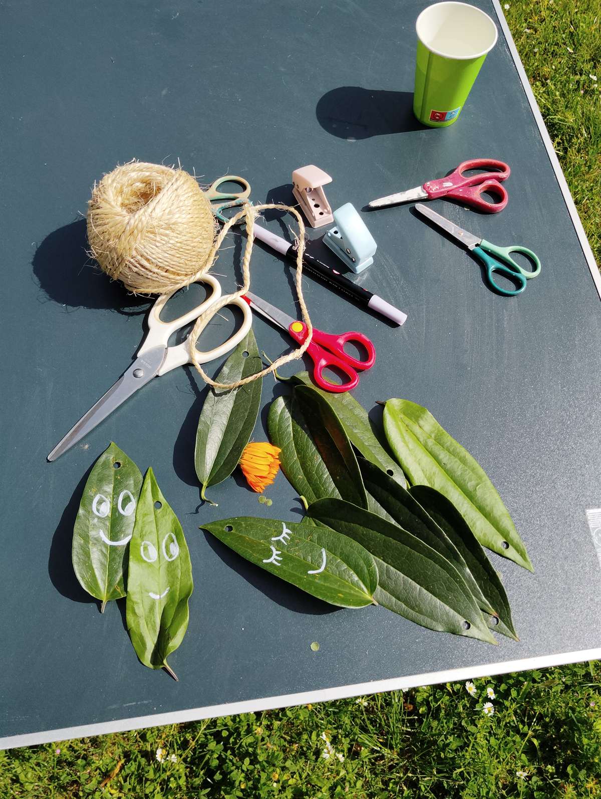 Feuilles décorées de petits visages souriants lors d'un atelier nature créatif