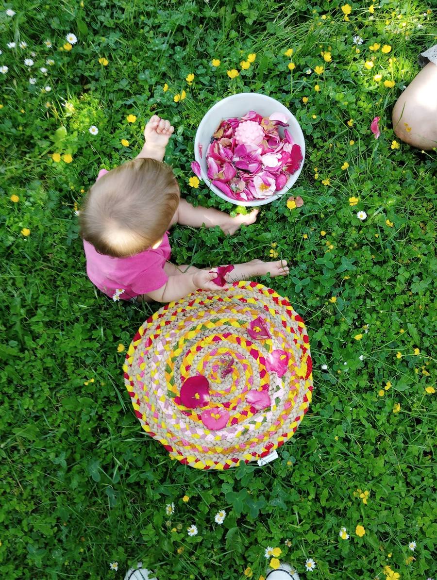 Bébé explorant des pétales de roses lors d'un atelier parents-enfants