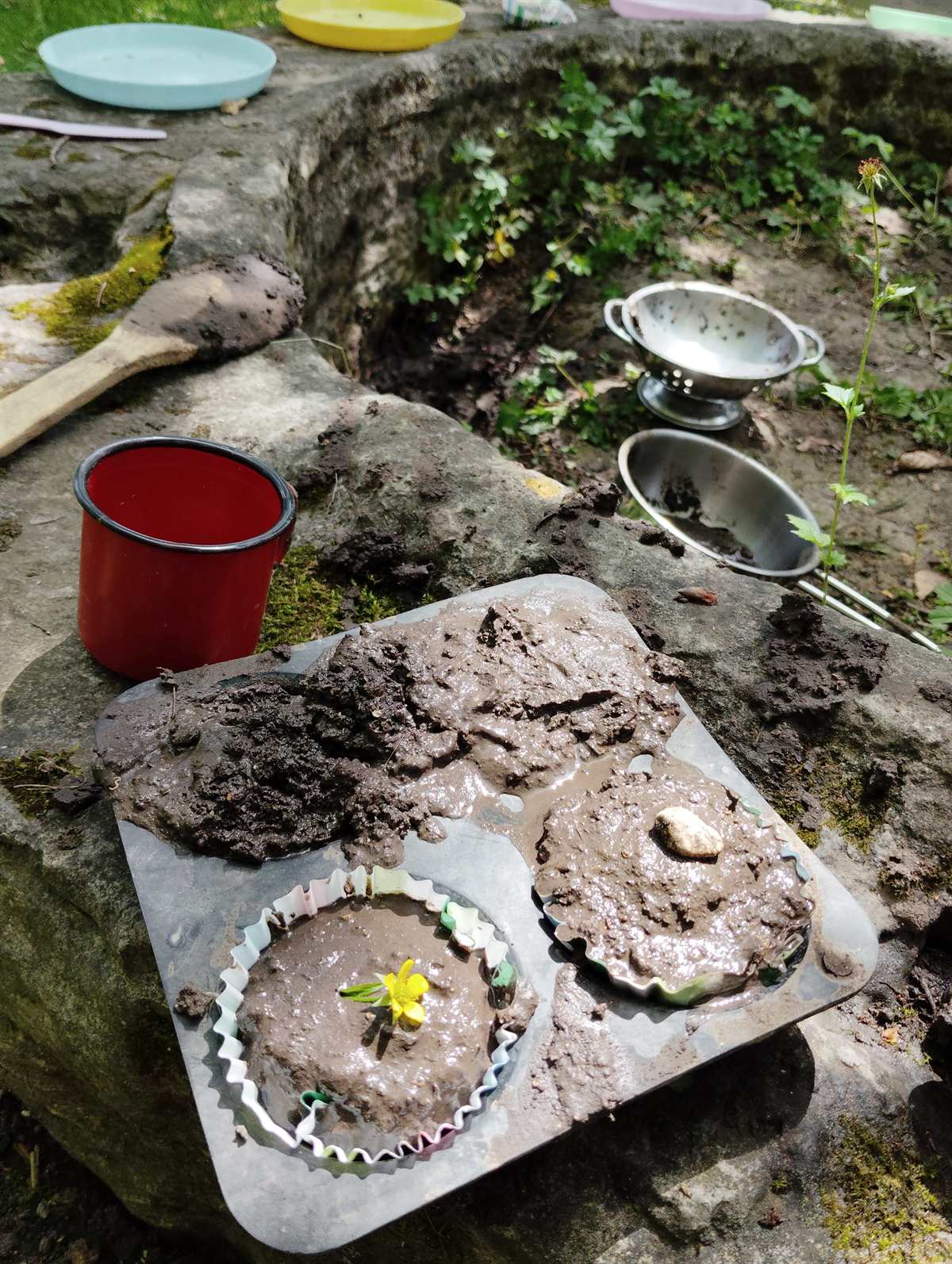 Petite cuisine de la nature : gâteaux de boue dans des moules à muffins, décorés d'une fleur