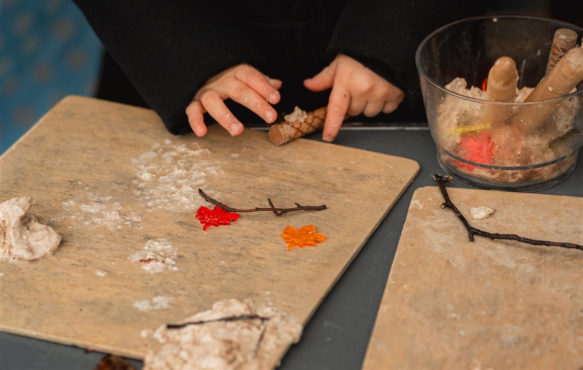 Mains d'enfant modelant de la pâte à sel avec des branches et des feuilles